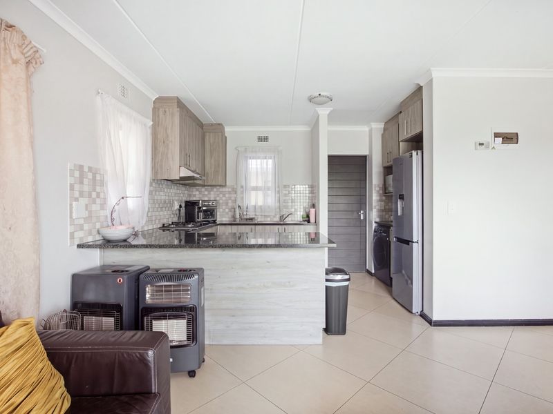 Open-plan kitchen featuring granite countertops, built-in cabinetry, and tiled flooring, seamlessly integrated into the living area.