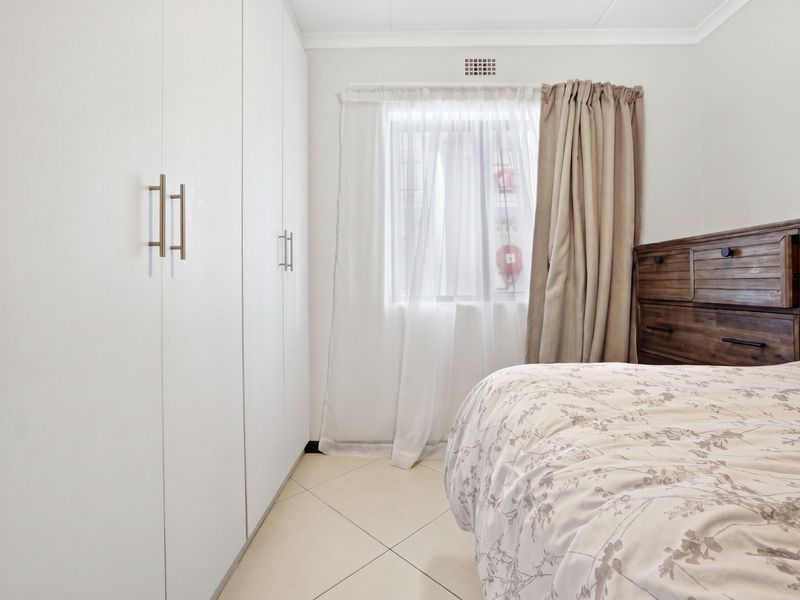 A well-maintained bedroom featuring neutral tiled flooring and ample built-in cupboard storage space.