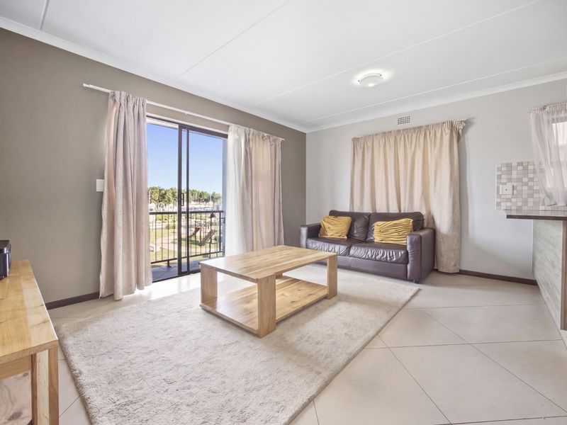 Open plan living area featuring tiled flooring, a breakfast bar with mosaic backsplash, and a sliding glass door leading to a balcony.
