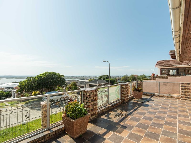 Spacious elevated balcony featuring tiled flooring, brick and glass balustrades, and expansive views of the surrounding neighborhood and coastline.