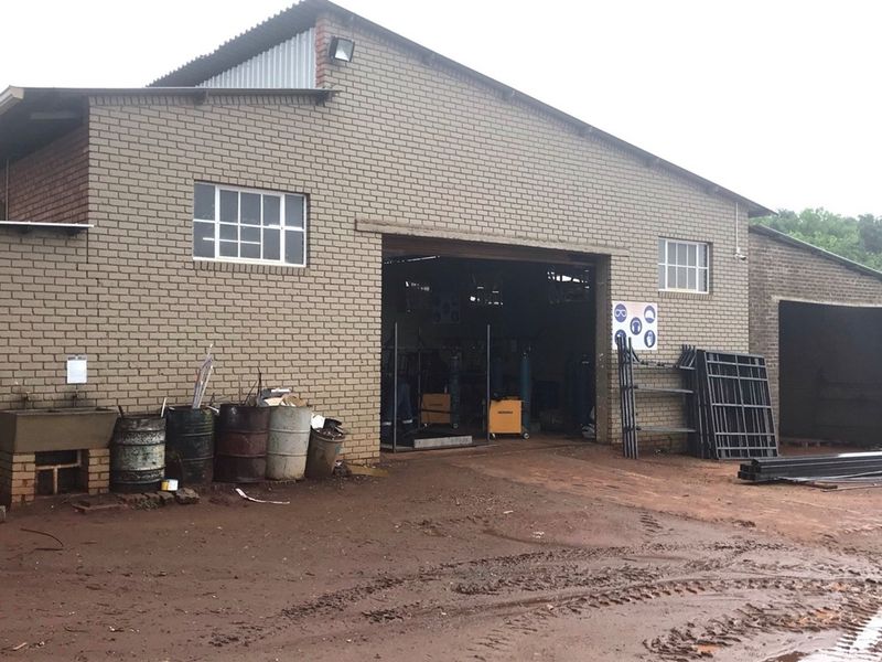 Large industrial utility shed or workshop featuring brick construction, a corrugated roof, and an external utility sink area.