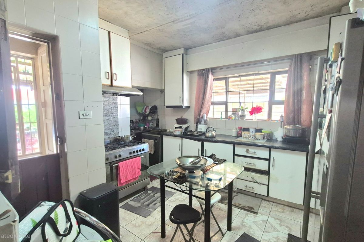 A dated kitchen featuring built-in cabinetry, a gas stove with extractor fan, and tiled finishes, offering significant potential for modernization and renovation.