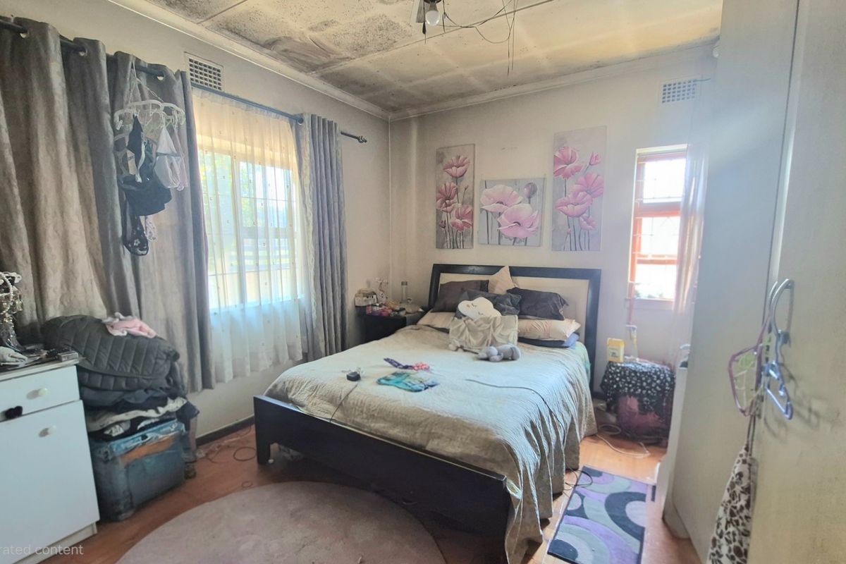 A bedroom featuring a window and built-in storage, currently showing significant signs of ceiling water damage and deterioration requiring repair.