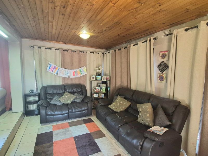 A living room featuring a timber tongue and groove ceiling and ceramic tiled flooring, offering a dated aesthetic ready for modernization.