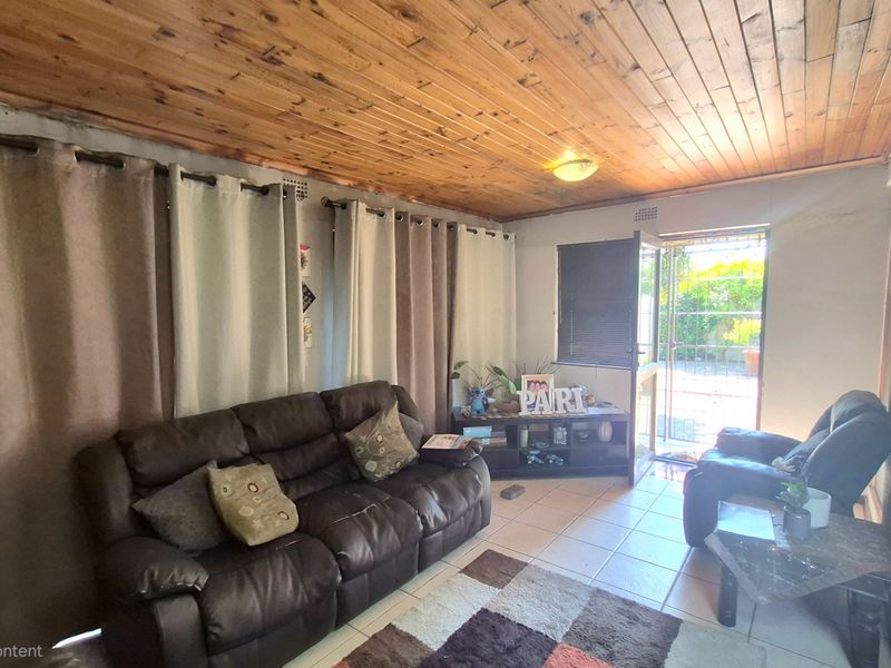 Living room featuring a timber tongue and groove ceiling, ceramic tiled flooring, and direct access to the exterior through a security gate.