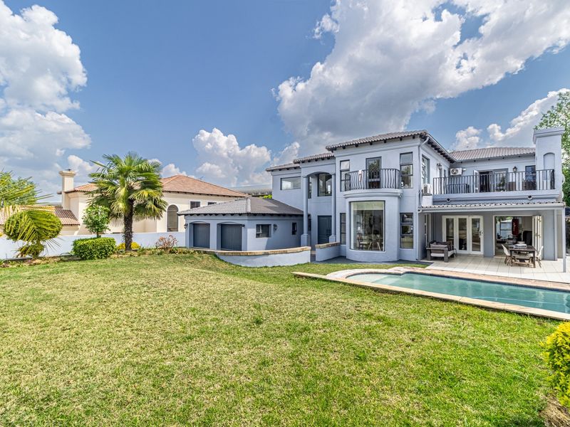 Rear view of a two-story house featuring a swimming pool, covered patio, upper-level balcony, and a well-maintained garden.