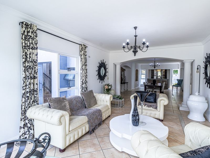 Spacious open-plan living area featuring tiled flooring, decorative columns, and an elegant archway leading to the dining space.
