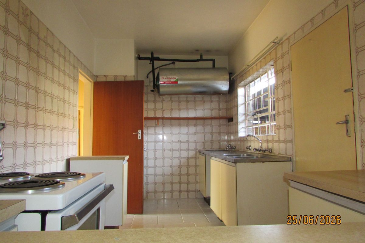 A functional kitchen featuring tiled walls, built-in cabinetry, a stainless steel sink, and an electric stove, offering a blank canvas for modern renovation.