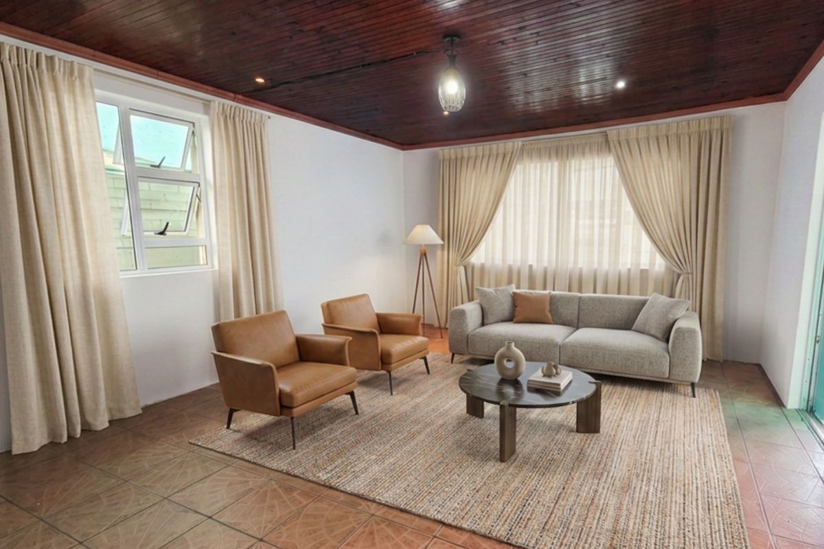 A spacious living room featuring a distinctive dark timber-clad ceiling, tiled flooring, and large windows that provide ample natural light.