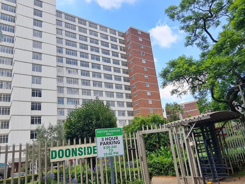 Exterior view of the Doonside residential building complex featuring security fencing, gated access, and established landscaping.