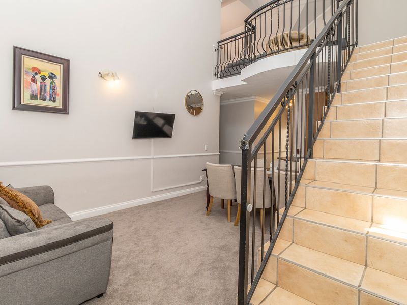 A living area featuring a tiled staircase with wrought iron railings, leading up to a mezzanine level with matching balustrades.