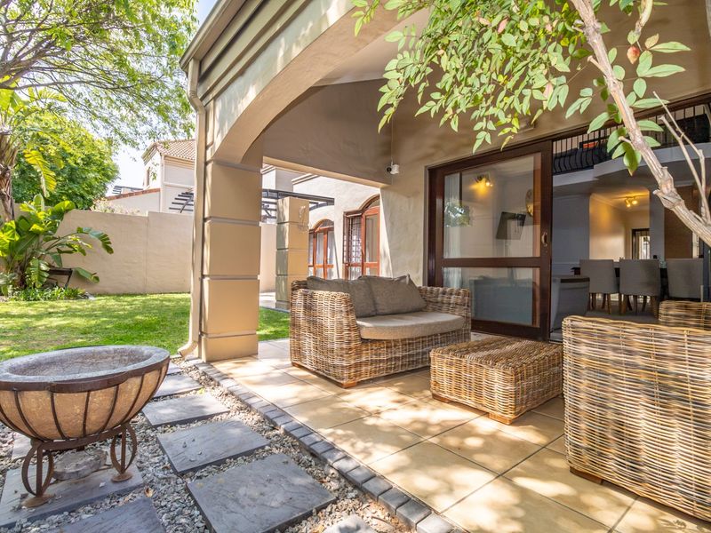 A covered patio area featuring tiled flooring and an archway, providing seamless access to the garden through large sliding glass doors.