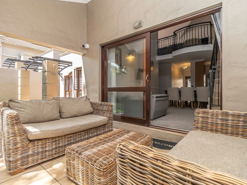 Covered patio area featuring tiled flooring and sliding door access to the interior living space with a visible mezzanine level.