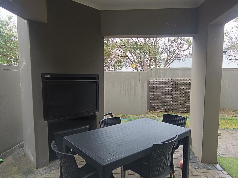 Covered patio area featuring a built-in braai, paved flooring, and direct access to the rear garden space.