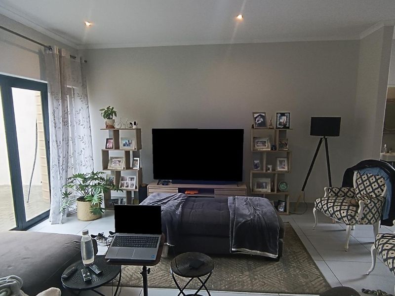 A comfortable living room featuring tiled flooring, recessed downlights, and large sliding glass doors that provide access to the outdoor area.