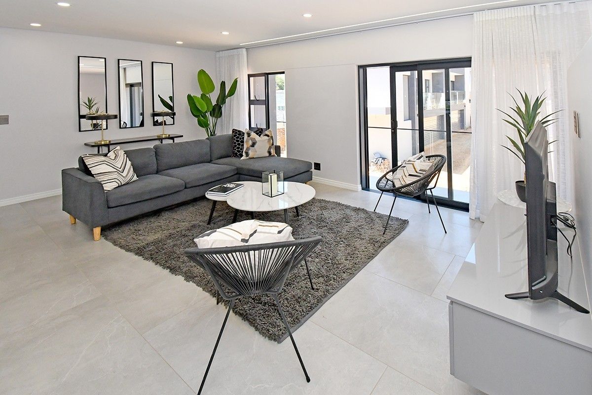 Modern, bright living room featuring large format floor tiles, recessed lighting, and sliding glass doors providing access to the exterior.