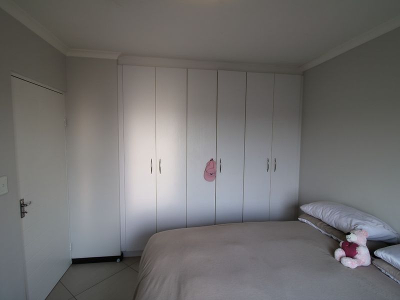 A well-maintained bedroom featuring neutral wall tones, tiled flooring, and ample built-in cupboard storage space.