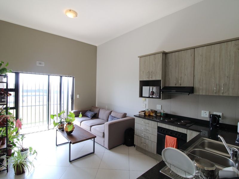 Modern open-plan living area featuring a well-appointed kitchen with granite countertops, built-in appliances, and direct access to a balcony through sliding glass doors.