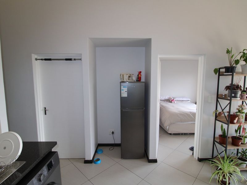 Open plan living area featuring tiled flooring, a dedicated fridge alcove, and direct access to an adjoining bedroom.