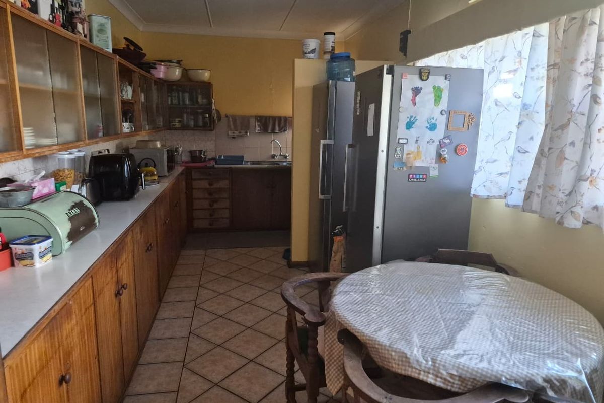 A functional kitchen featuring extensive wooden cabinetry, laminate countertops, a double sink, and tiled flooring, offering potential for a modern renovation.