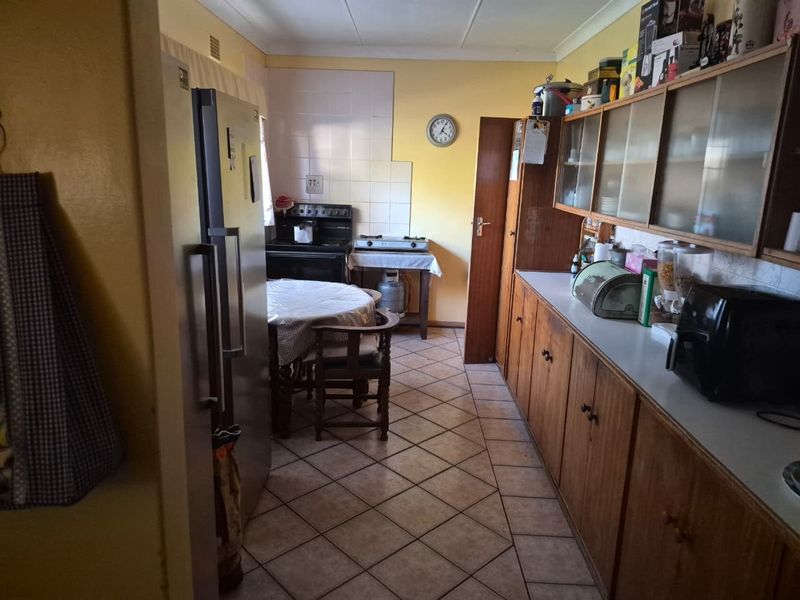 A functional kitchen featuring traditional wooden cabinetry, tiled flooring, and a gas stove, offering potential for a modern cosmetic update.