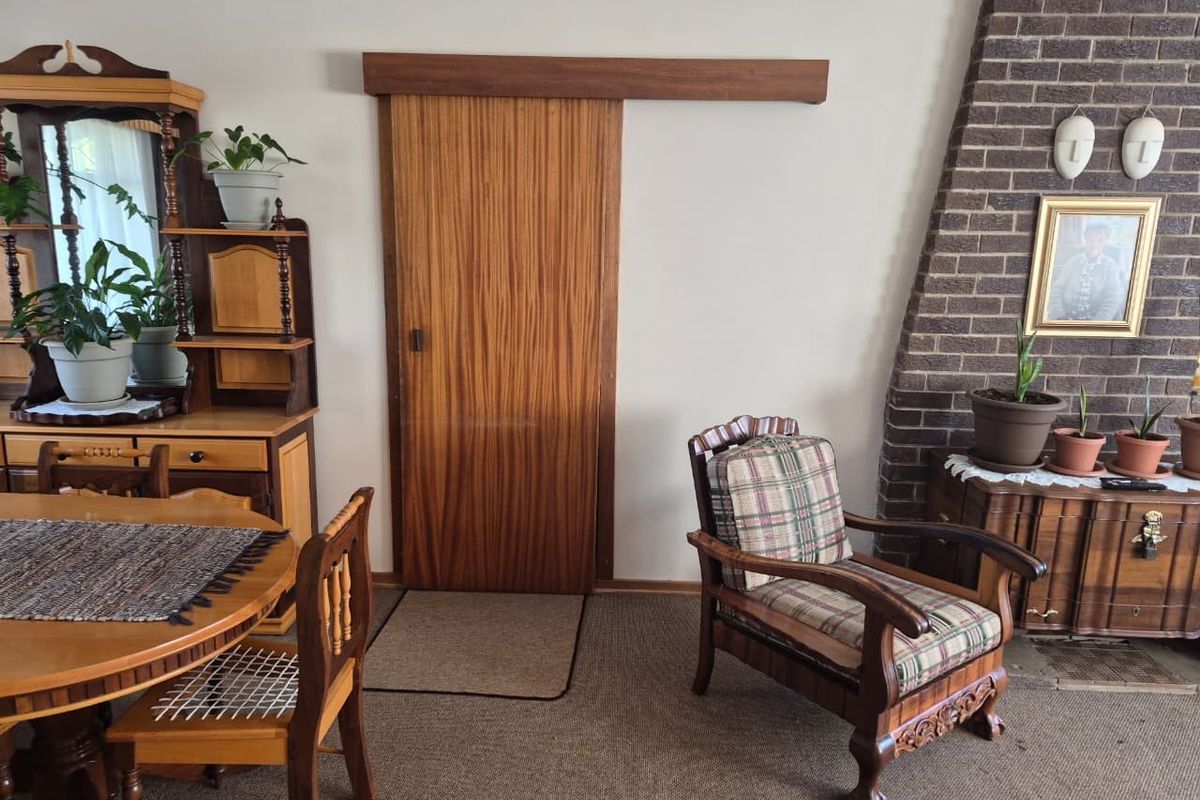 Living room featuring a brick fireplace and a sliding wooden door, offering a traditional aesthetic with carpeted flooring.