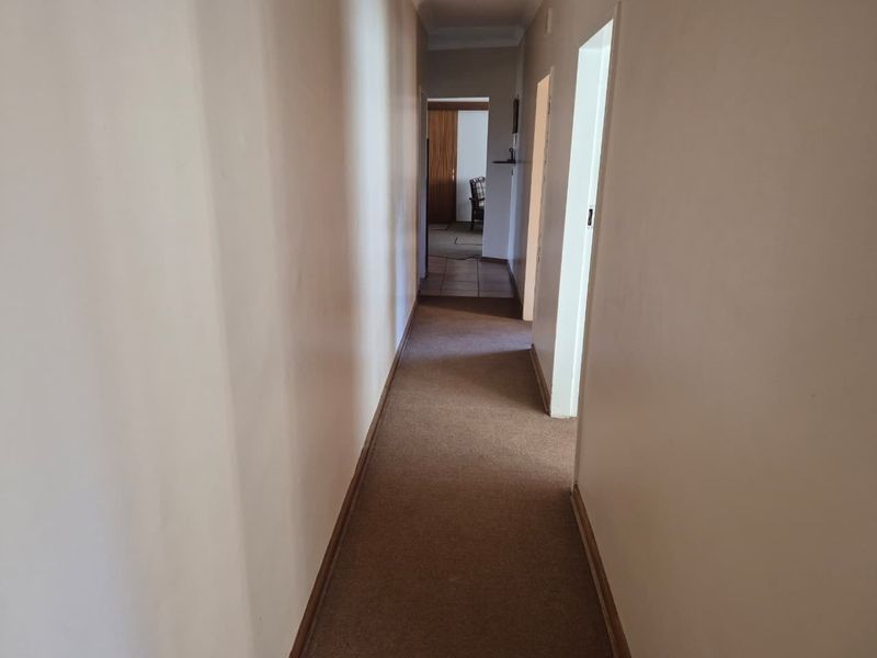 A functional residential hallway featuring carpeted flooring and neutral wall finishes, providing access to adjacent rooms within the property.