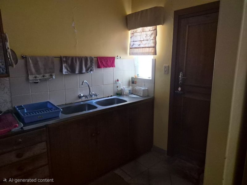 A functional scullery area featuring a double basin sink, tiled splashback, and built-in cabinetry, requiring some cosmetic updates to the wall finishes.