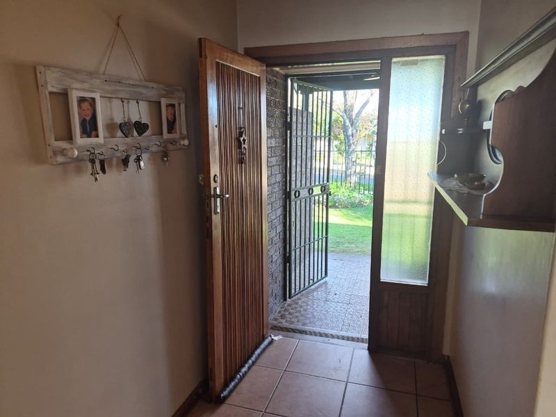 Entrance hall featuring tiled flooring, a solid wooden front door, and a security gate leading to the exterior.