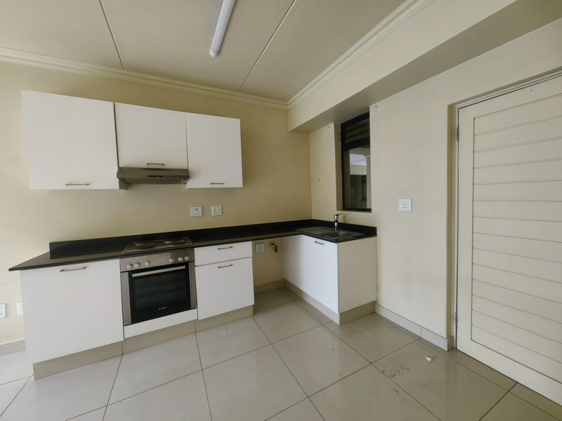 A functional kitchen featuring white cabinetry, granite countertops, a built-in oven, hob, extractor fan, and tiled flooring.