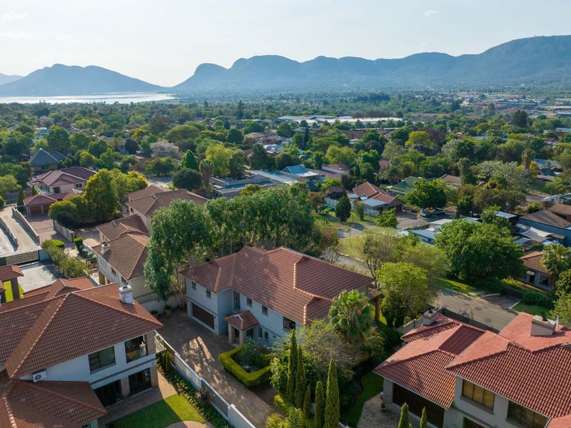 An elevated aerial view of the residential property, showcasing the roof structure, driveway, and surrounding neighbourhood landscape with mountain views.
