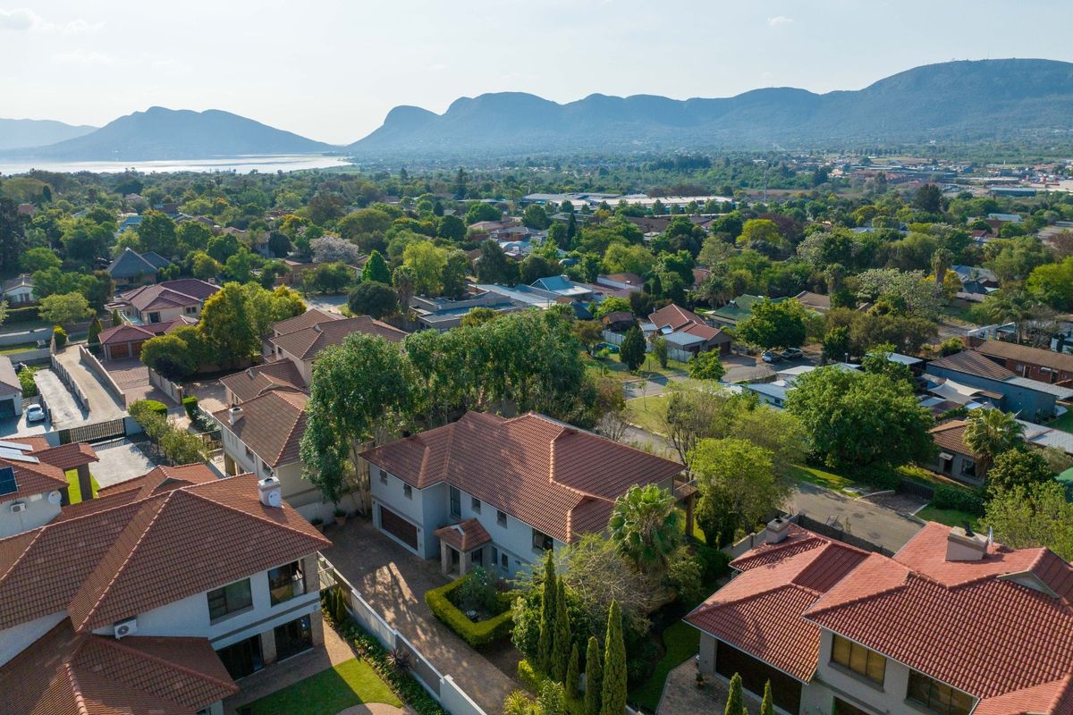 An elevated aerial view of the residential property, showcasing the roof structure, driveway, and surrounding neighbourhood landscape with mountain views.