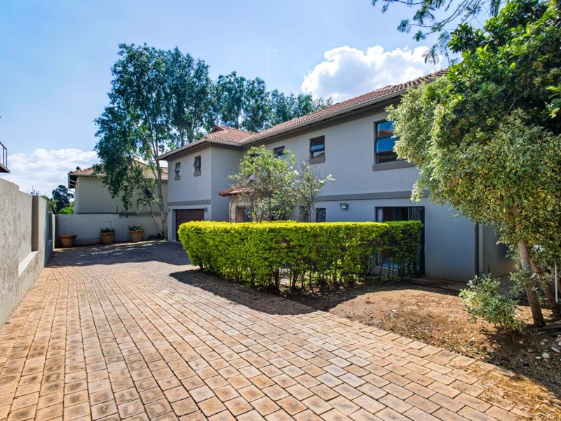 Front exterior view of a two-story house featuring a paved driveway, established hedging, and a tiled roof.