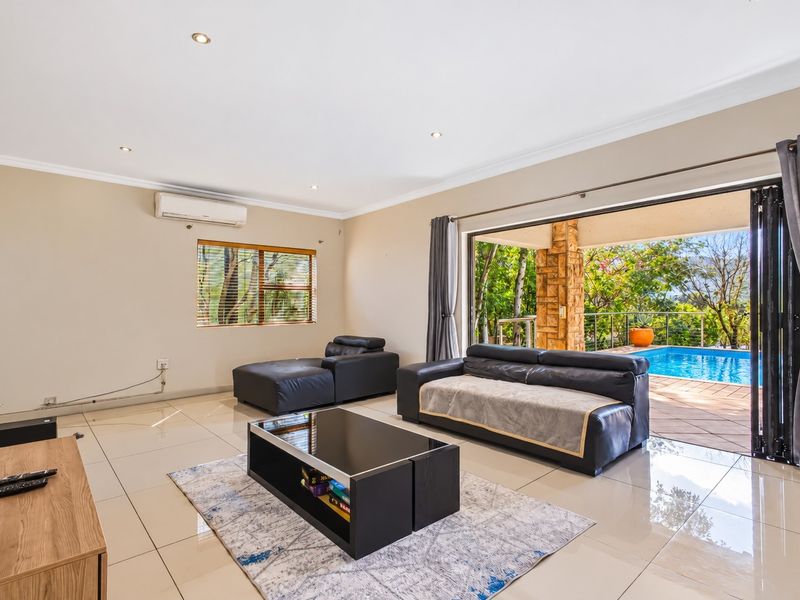 Spacious living room featuring large sliding glass doors that open to a patio and pool area, with tiled floors and integrated air conditioning.
