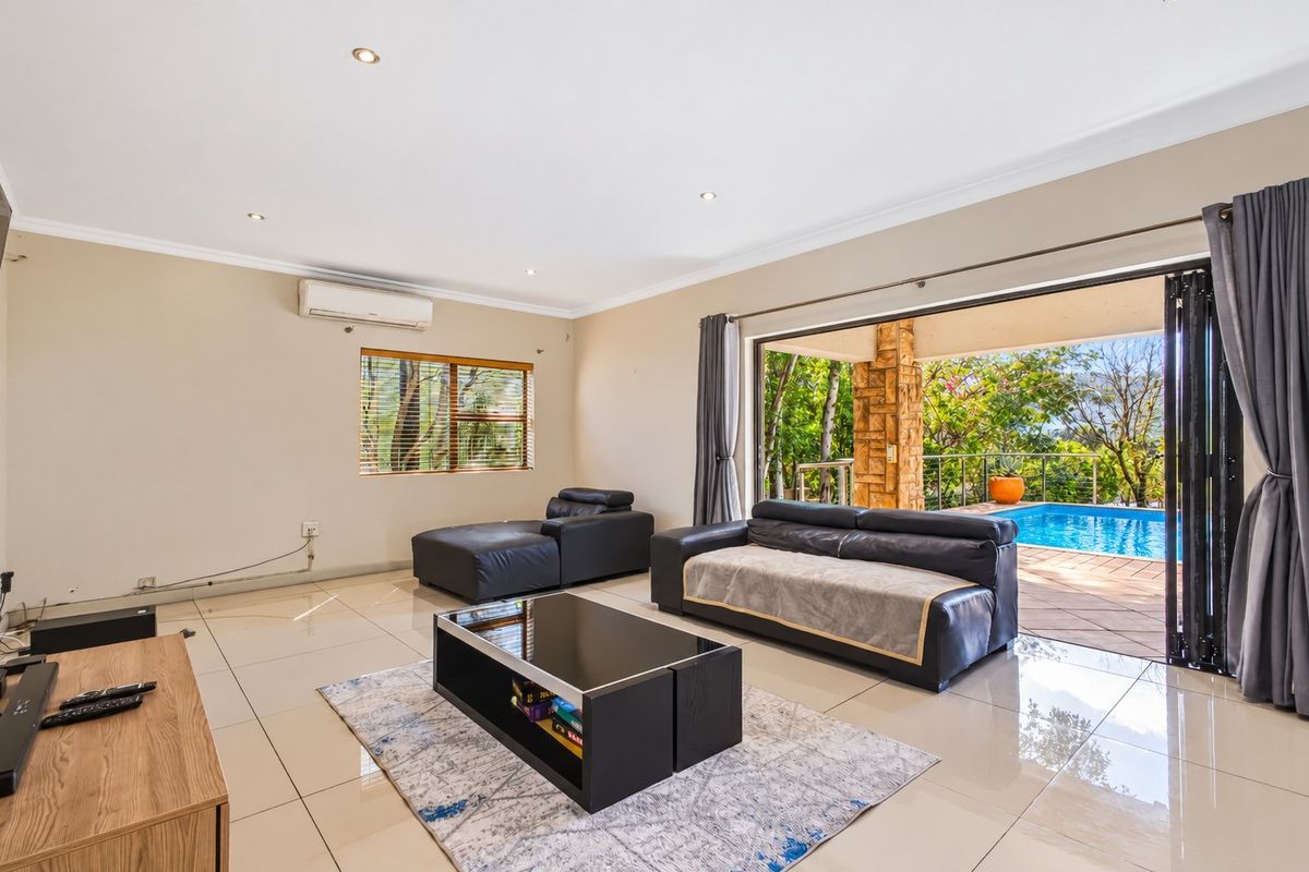 Spacious living room featuring large sliding glass doors that open to a patio and pool area, with tiled floors and integrated air conditioning.
