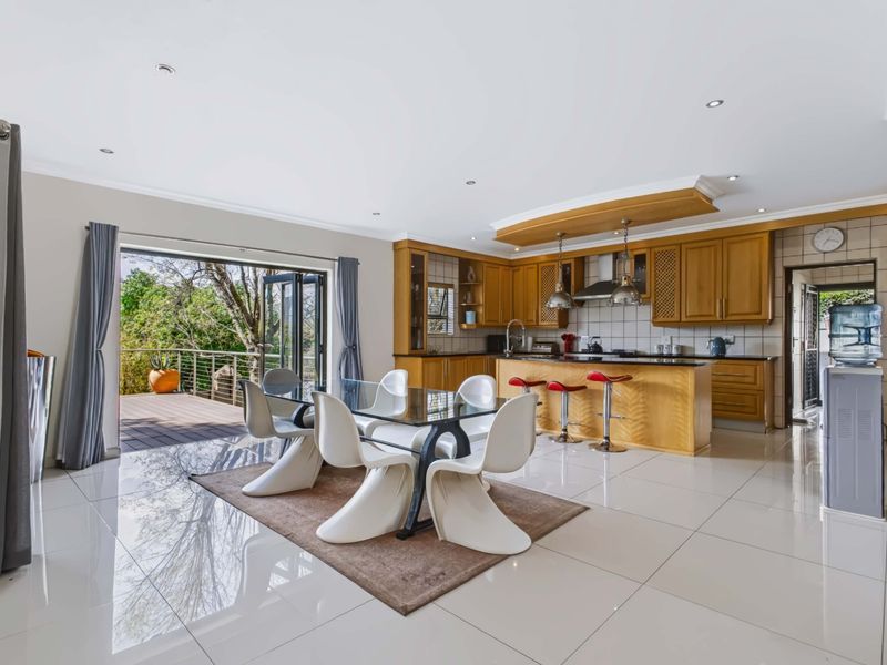 Spacious open-plan kitchen and dining area featuring wooden cabinetry, granite countertops, and large sliding doors opening onto an outdoor deck.