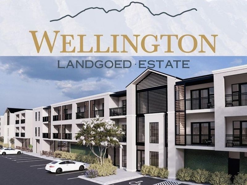 A modern apartment complex exterior featuring contemporary architectural design, private balconies with metal railings, and a paved parking area.