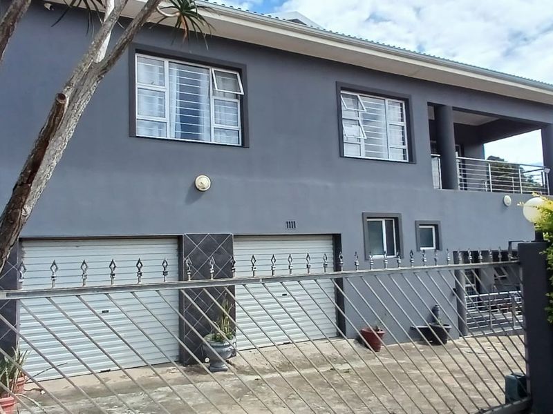 Front elevation of a two-story house featuring a double garage, upper-level balcony, and secure metal perimeter fencing.