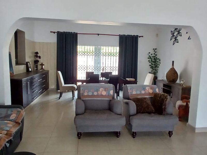 Spacious open-plan living and dining area featuring neutral tiled flooring and a distinctive arched architectural transition between the two zones.