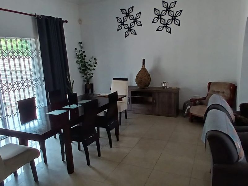 Spacious open-plan living and dining area featuring tiled flooring and a large sliding glass door with security gate leading to the exterior.