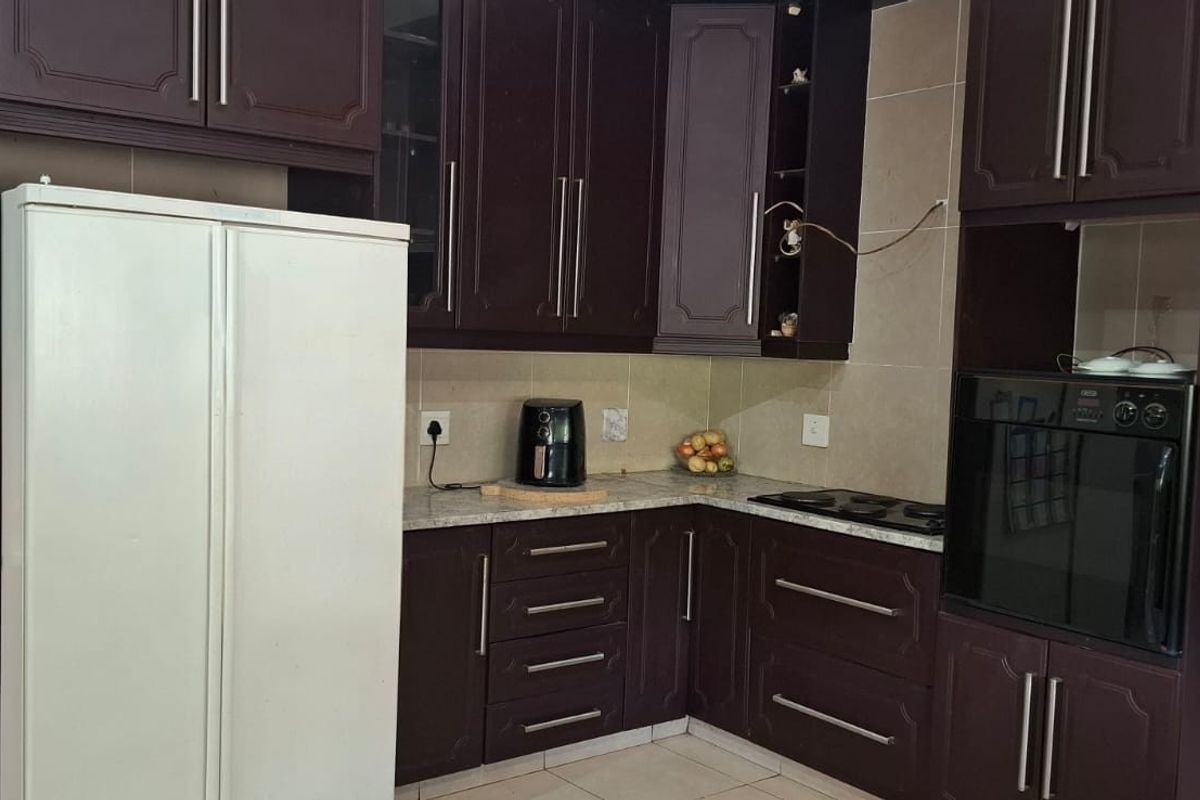 A functional kitchen featuring dark wood cabinetry, stone countertops, a built-in oven, and a hob with a tiled backsplash.