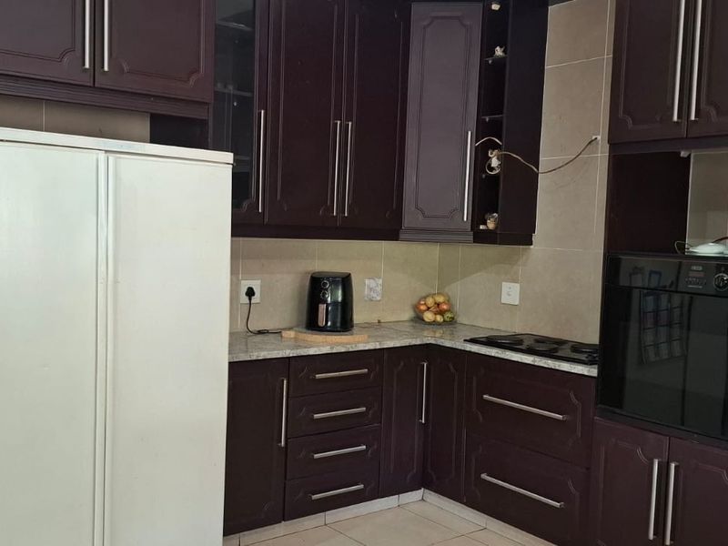 A functional kitchen featuring dark wood cabinetry, stone countertops, a built-in oven, and a hob with a tiled backsplash.