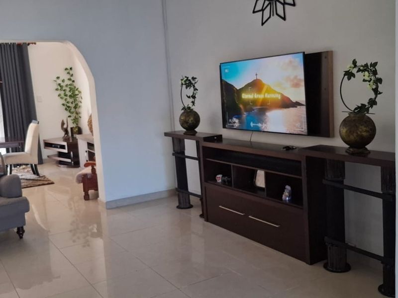 A spacious living area featuring polished tile flooring and an arched entryway leading to an adjacent dining space with security gate access.