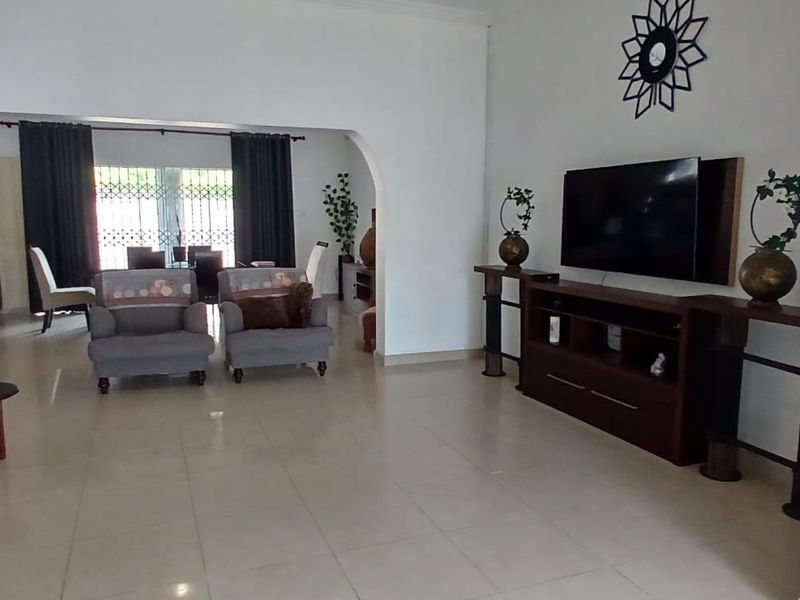 Spacious open-plan living area featuring tiled flooring and an arched transition to the adjacent dining space.