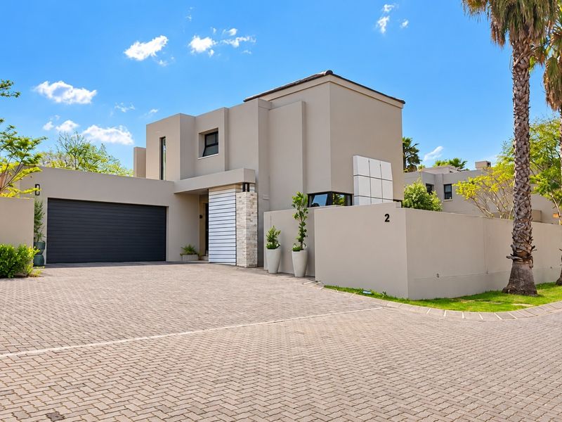 Modern double-story residence featuring a clean architectural facade, stone accents, a spacious paved driveway, and an integrated double garage.