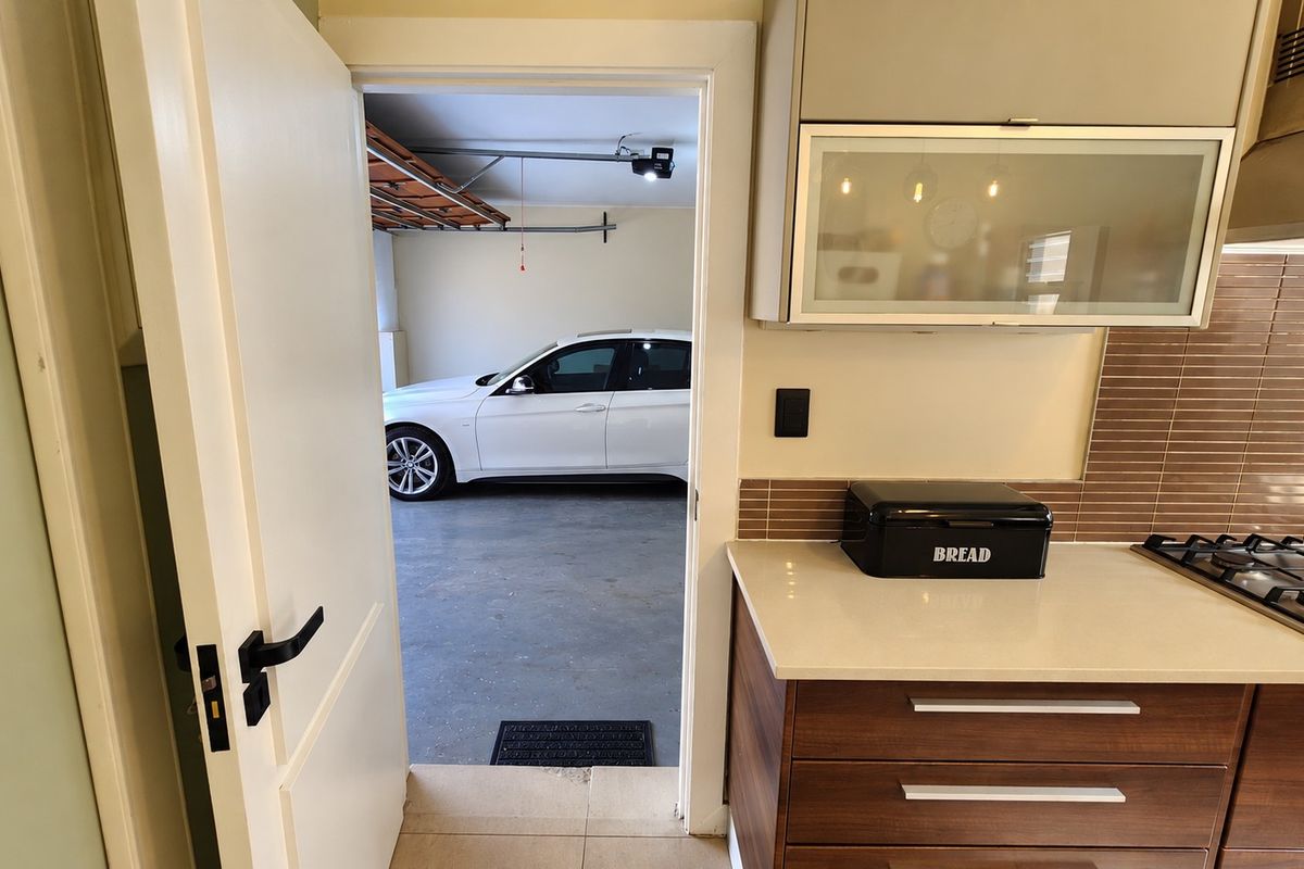 A modern kitchen featuring stone countertops, a gas hob, and an extractor fan, with direct access to the garage.