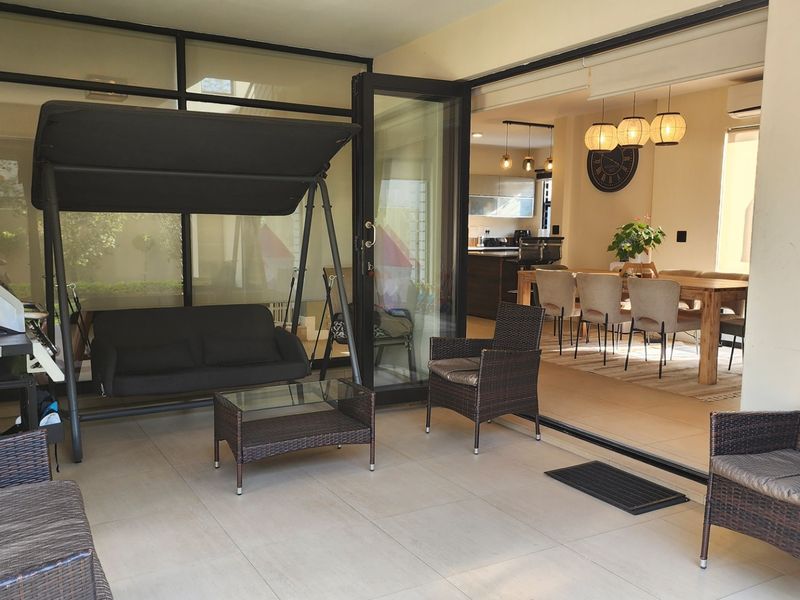 A covered patio area featuring large stacking glass doors that open into the interior living space, creating a seamless indoor-outdoor flow.