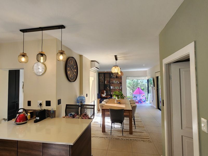 An open-plan living and dining area featuring a modern kitchen island with stone countertops, pendant lighting, and tiled flooring throughout.