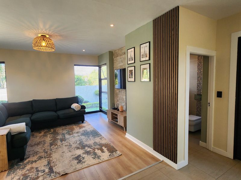 Modern living room featuring a stylish timber slat feature wall, stone accent wall, and laminate flooring, with direct access to an adjacent bathroom.