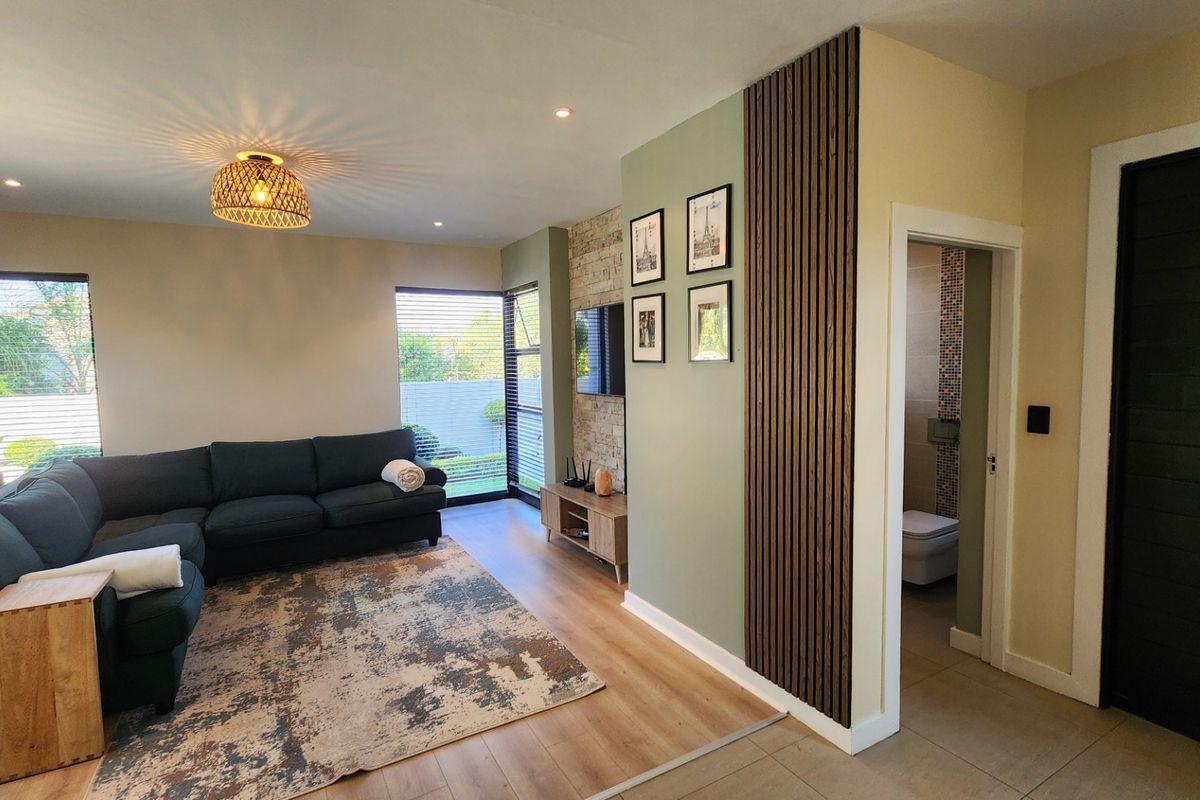 Modern living room featuring a stylish timber slat feature wall, stone accent wall, and laminate flooring, with direct access to an adjacent bathroom.